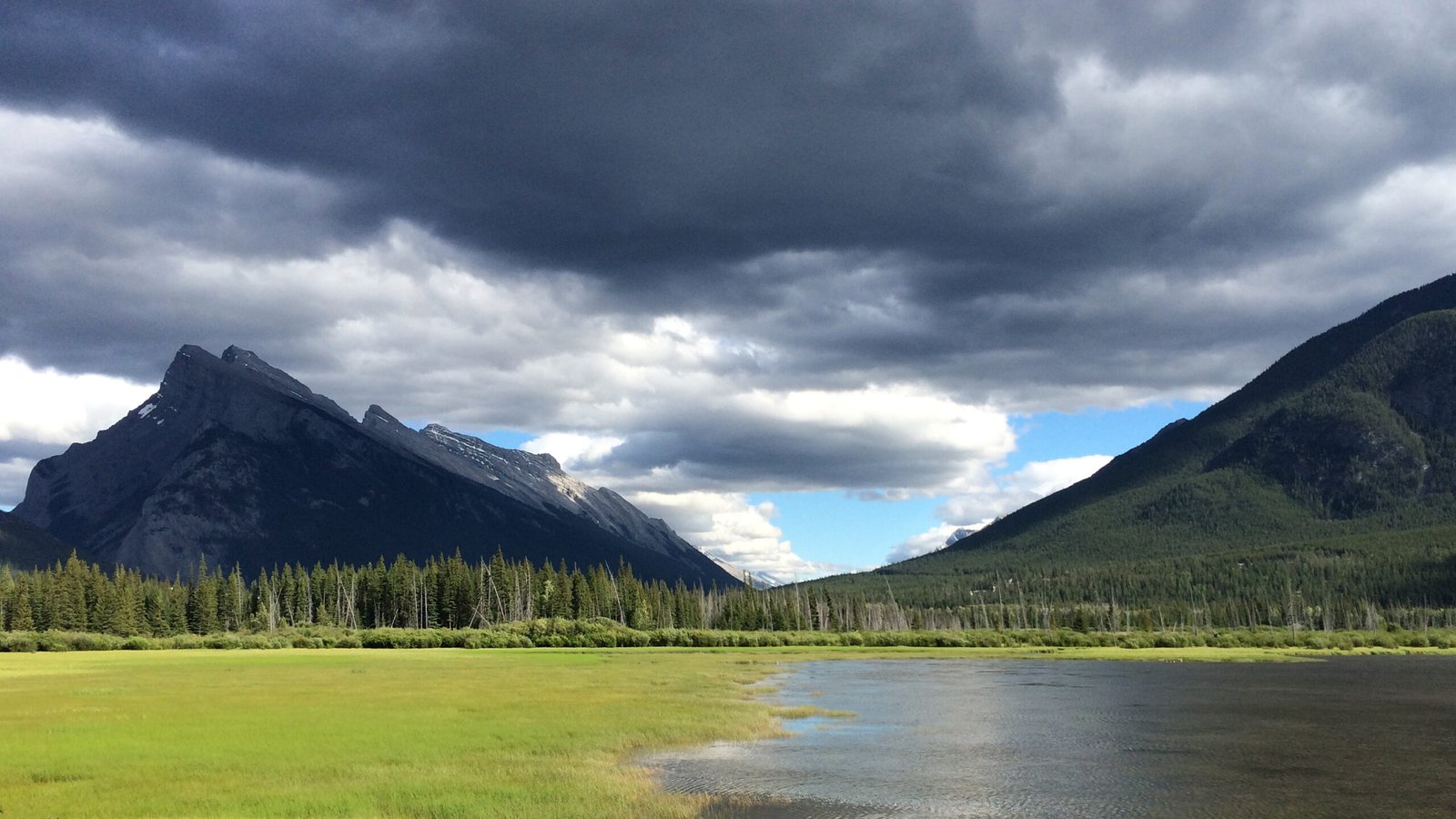 Storm clouds over Vermilion Lakes with forest and mountain peaks in Banff National Park, Alberta, Canada